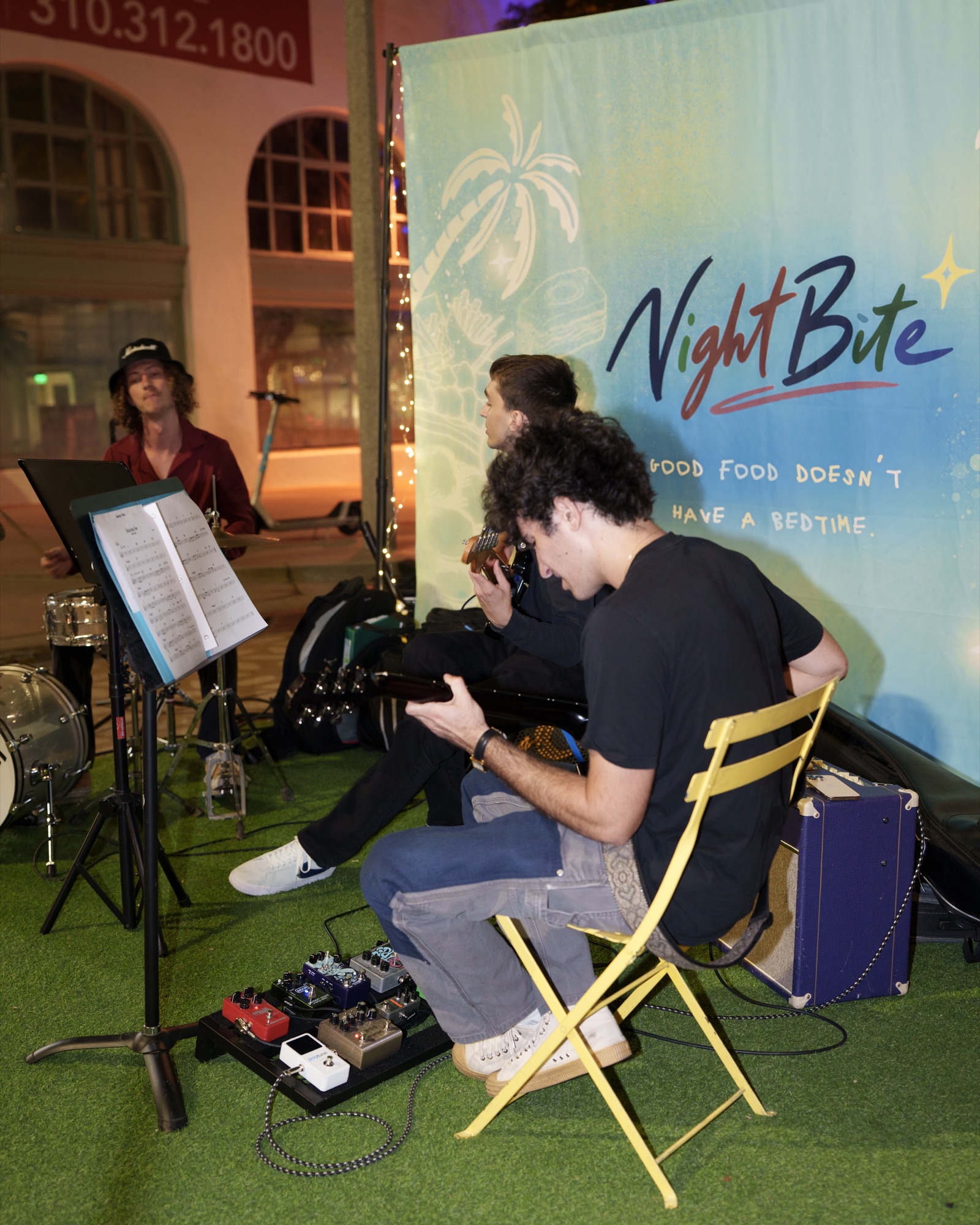 Musicians playing in front of the NightBite backdrop